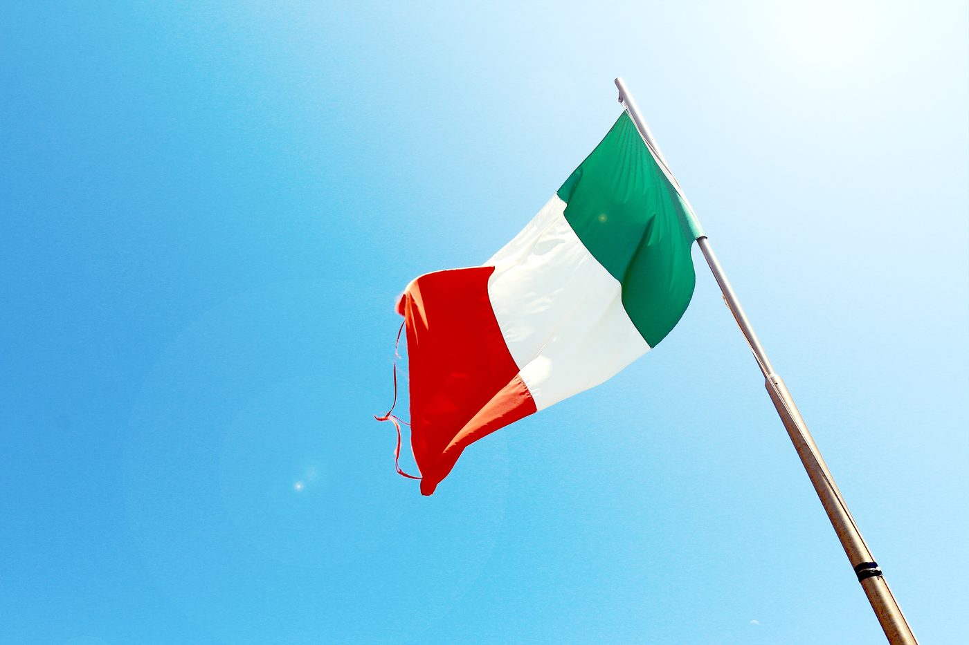 The Italian flag waving against a clear blue sky